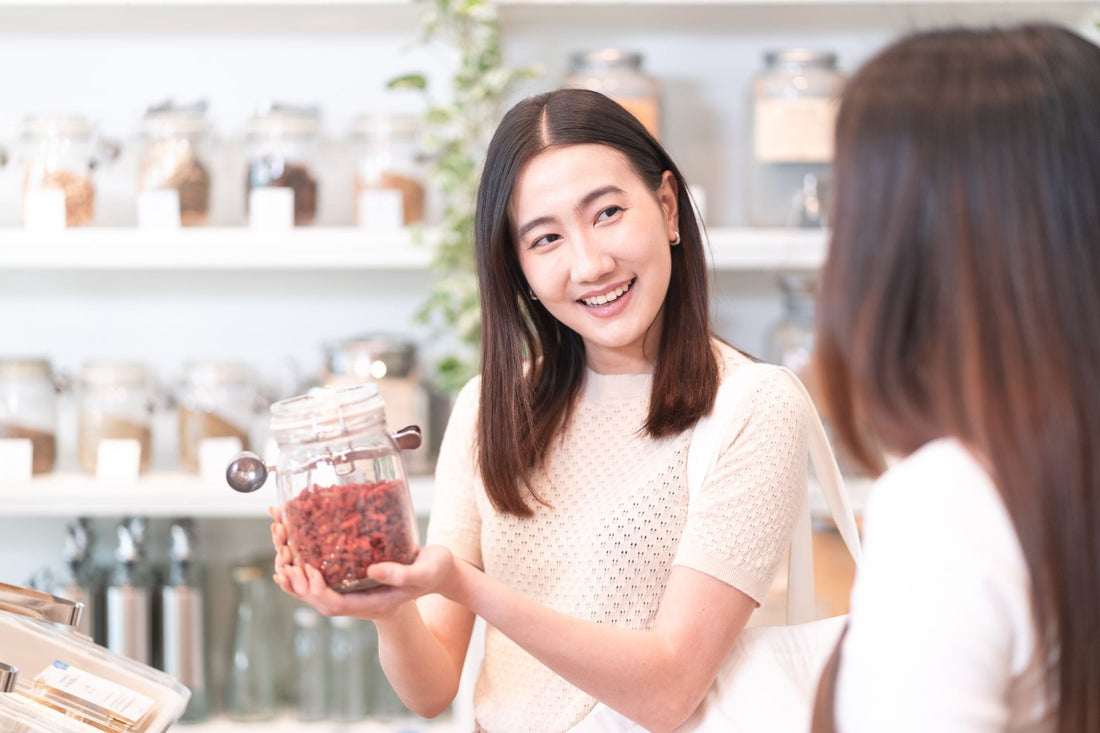 Woman holding a jar of dried goji berries while learning about Traditional Chinese Medicine (TCM) and natural wellness.